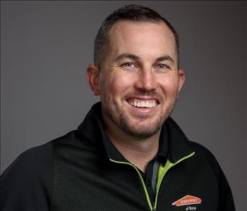 Male Employee smiling in front of a grey back ground 