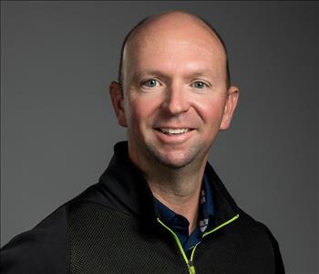 Male Employee smiling in front of a grey back ground 